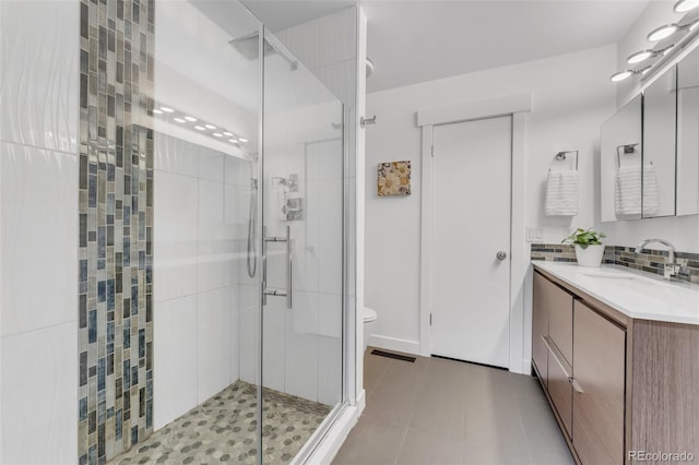 445 Wintery Cir, Colorado Springs, CO 80919 - full bathroom with a shower stall, vanity, toilet, tile patterned floors, and decorative backsplash