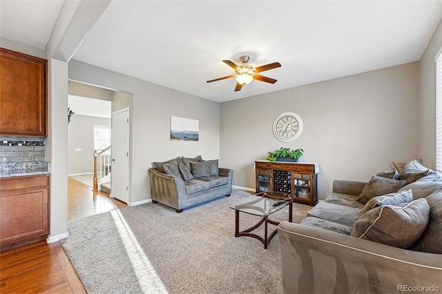 living room featuring baseboards, wood finished floors, and ceiling fan