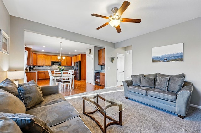 living room with ceiling fan, light colored carpet, recessed lighting, beverage cooler, and baseboards