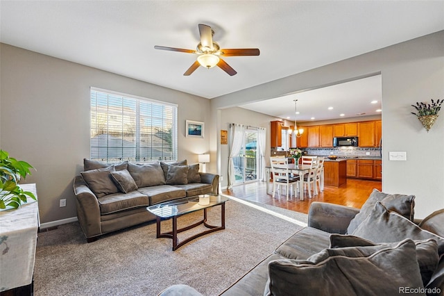 living area with baseboards, recessed lighting, and ceiling fan with notable chandelier