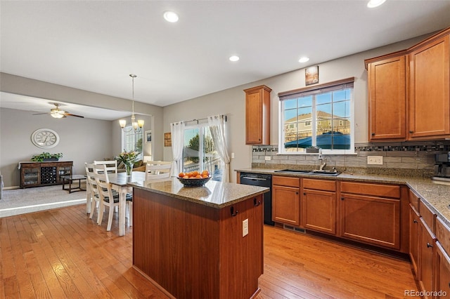 kitchen with light wood-type flooring, black dishwasher, a kitchen island, brown cabinetry, and a sink