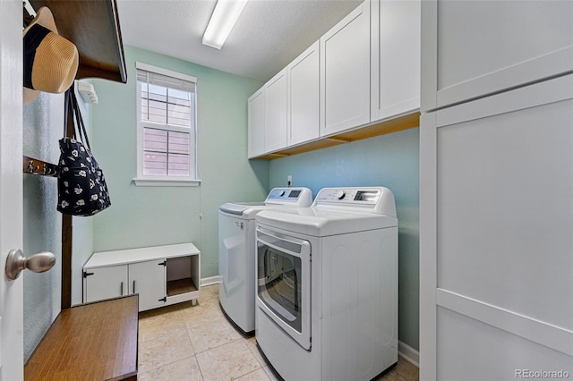 clothes washing area with cabinet space, light tile patterned floors, washer and clothes dryer, and baseboards