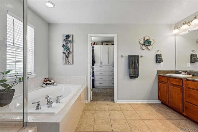 bathroom featuring tile patterned flooring, vanity, baseboards, and a garden tub