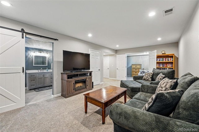 living area with visible vents, baseboards, a barn door, recessed lighting, and light carpet