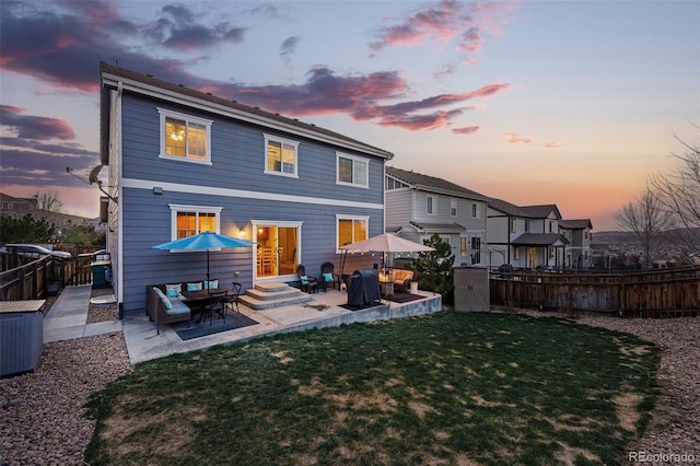 back of property at dusk with a yard, a fenced backyard, entry steps, and a patio