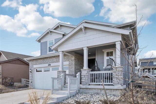 craftsman house featuring driveway, stone siding, a garage, and a porch