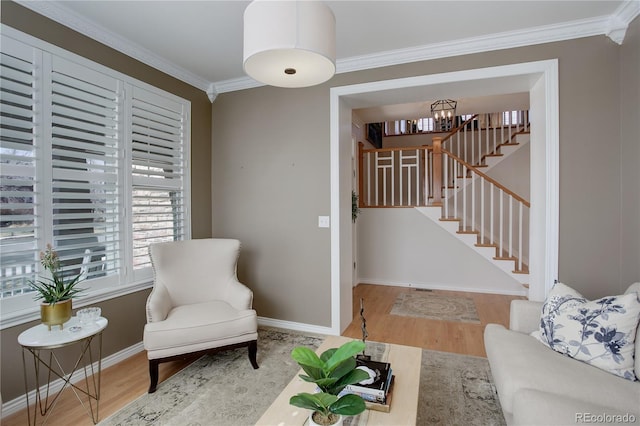 living area featuring a notable chandelier, crown molding, wood finished floors, baseboards, and stairs