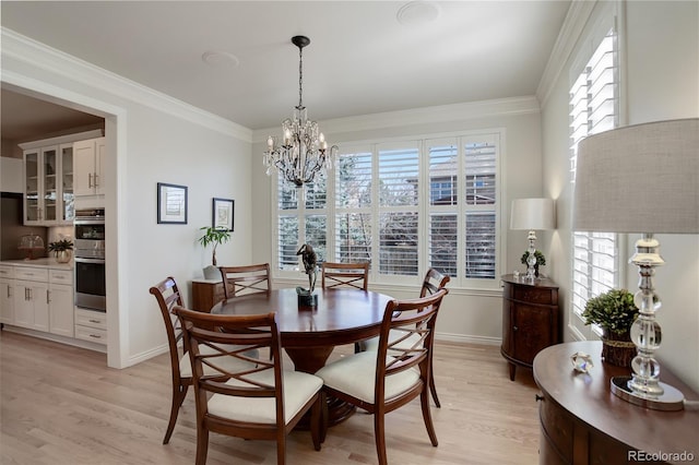 dining area with baseboards, light wood-style floors, an inviting chandelier, and crown molding