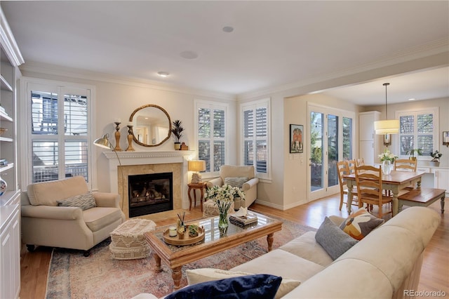 living room with light wood-style floors, a high end fireplace, and ornamental molding