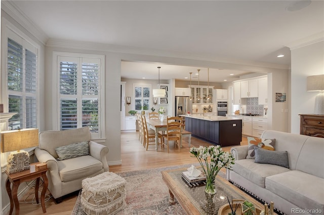 living area featuring light wood finished floors, ornamental molding, and recessed lighting