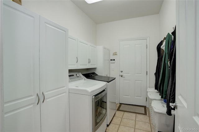 clothes washing area with light tile patterned floors, cabinet space, and washer and dryer