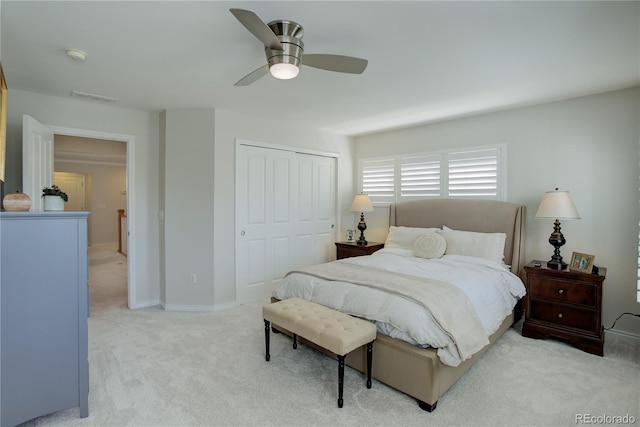 bedroom with a closet, light colored carpet, visible vents, ceiling fan, and baseboards