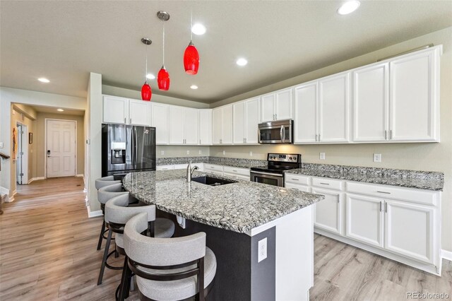13113 W 73rd Ave, Arvada, CO 80005 - kitchen with appliances with stainless steel finishes, a sink, white cabinetry, and light wood-type flooring
