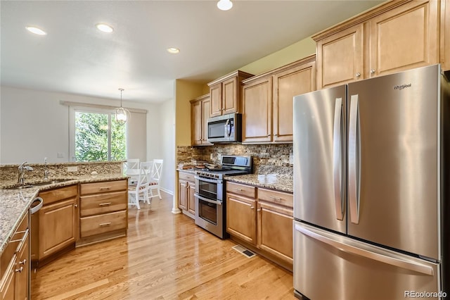 kitchen featuring light stone counters, pendant lighting, tasteful backsplash, stainless steel appliances, and light wood-type flooring