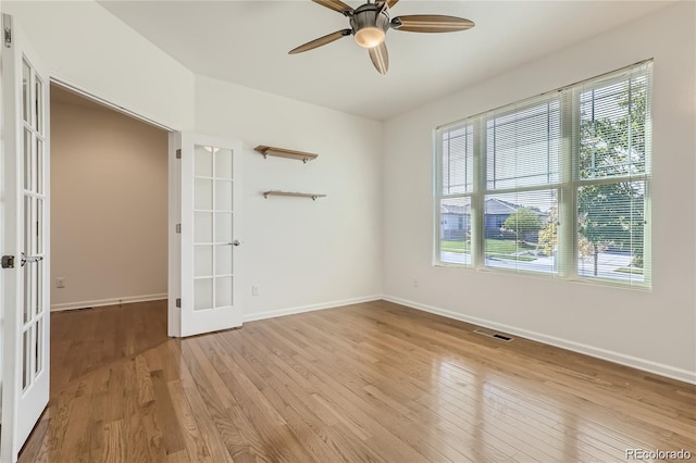 empty room with light hardwood / wood-style flooring, ceiling fan, and french doors