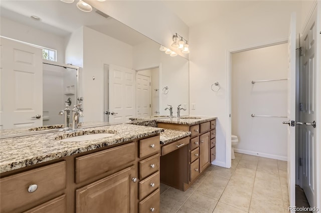 bathroom with tile patterned flooring, a shower with door, vanity, and toilet