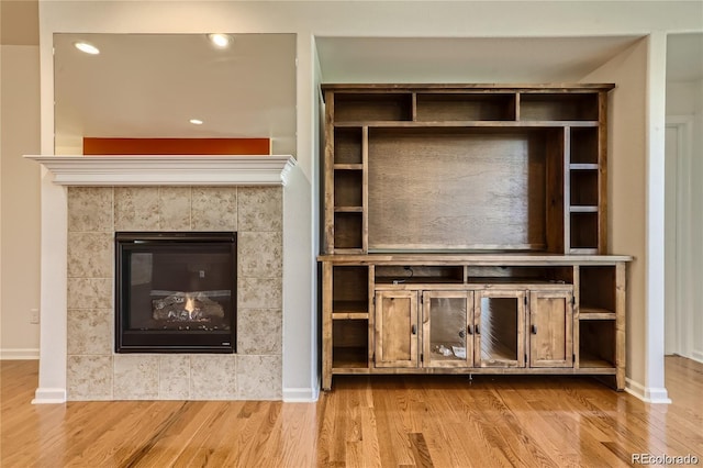 unfurnished living room with light hardwood / wood-style floors and a tiled fireplace