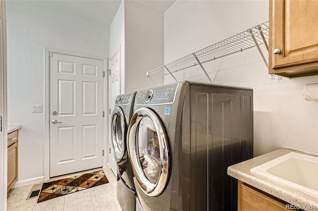 laundry area featuring cabinets, independent washer and dryer, light tile patterned flooring, and sink