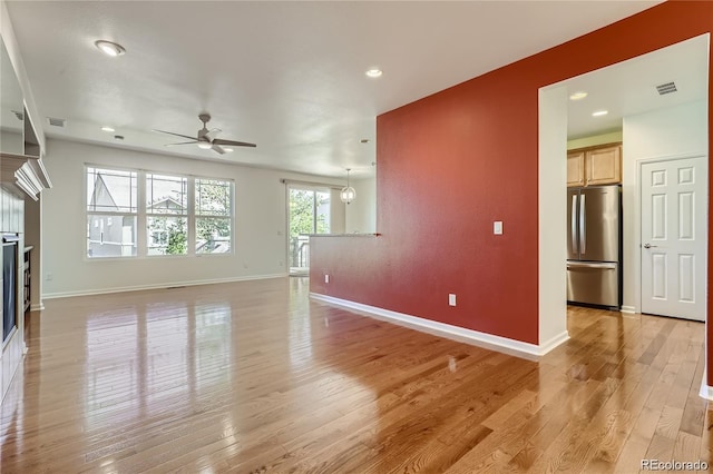 empty room with ceiling fan and light hardwood / wood-style floors