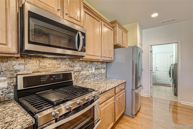 kitchen with light hardwood / wood-style flooring, stainless steel appliances, backsplash, and light stone countertops