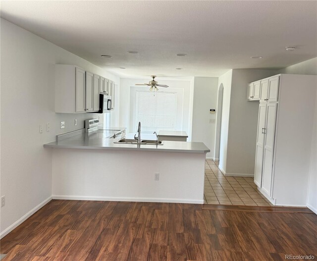 20401 E Chenango Pl, Aurora, CO 80015 - kitchen featuring electric range oven, a peninsula, arched walkways, wood finished floors, and stainless steel microwave