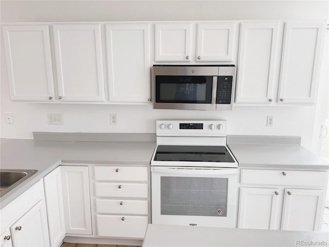 20401 E Chenango Pl, Aurora, CO 80015 - kitchen featuring stainless steel microwave, white electric range, light countertops, and white cabinetry