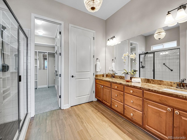 bathroom featuring vanity, a notable chandelier, and a shower with shower door