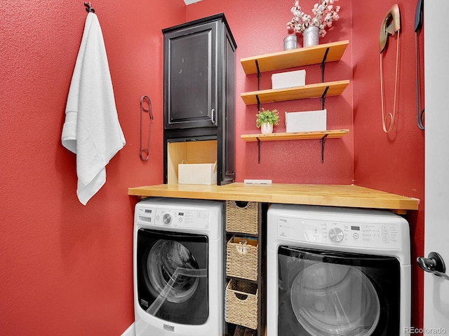 clothes washing area featuring cabinets and washing machine and clothes dryer