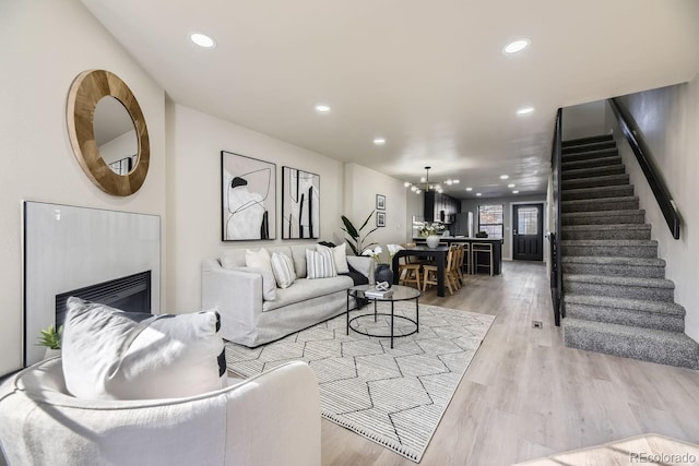 living area featuring light wood-style floors, recessed lighting, stairway, and a glass covered fireplace