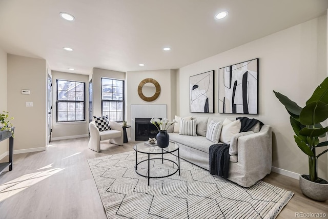 living room with light wood finished floors, a fireplace, baseboards, and recessed lighting