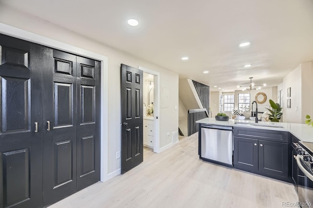 kitchen with stainless steel appliances, light wood-style floors, open floor plan, a sink, and a peninsula