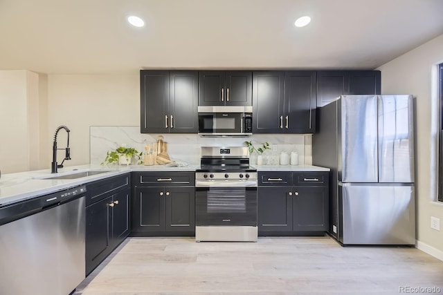 kitchen with stainless steel appliances, a sink, light stone counters, and tasteful backsplash