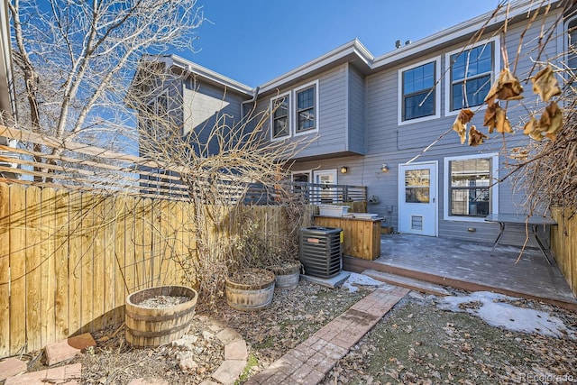 rear view of property featuring fence, a wooden deck, and central air condition unit