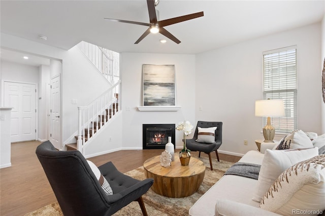 living area with recessed lighting, wood finished floors, a glass covered fireplace, stairs, and ceiling fan