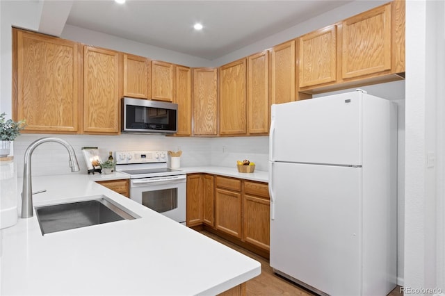 kitchen with light countertops, backsplash, a sink, and white appliances
