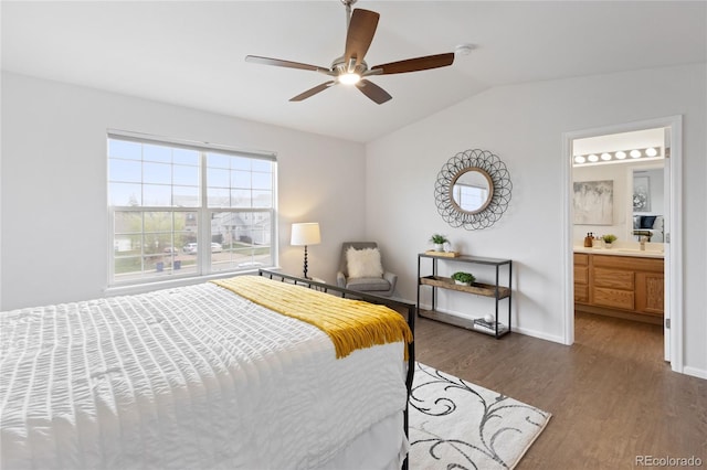 bedroom with vaulted ceiling, baseboards, a ceiling fan, ensuite bath, and dark wood-type flooring