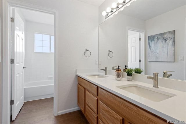 bathroom featuring baseboards, wood finished floors, a sink, and double vanity
