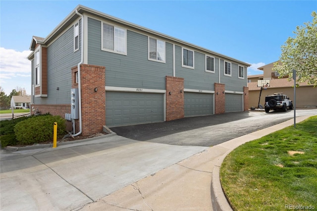 exterior space featuring brick siding, driveway, and a garage