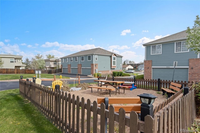 view of community with fence, an attached garage, and a residential view