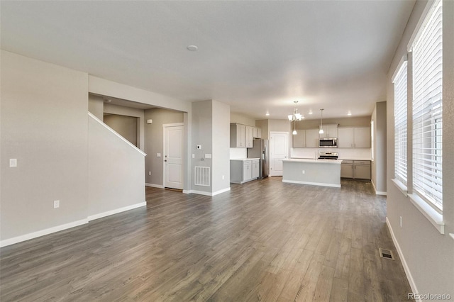 unfurnished living room with dark wood-type flooring and a notable chandelier