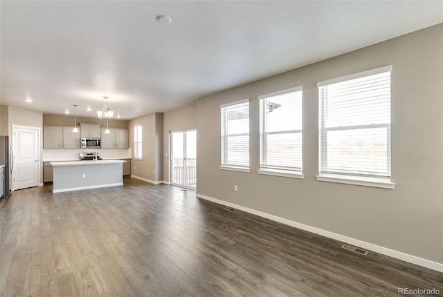 unfurnished living room featuring dark hardwood / wood-style floors and an inviting chandelier