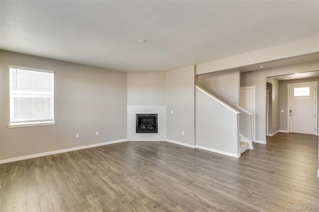 unfurnished living room featuring hardwood / wood-style flooring and a brick fireplace