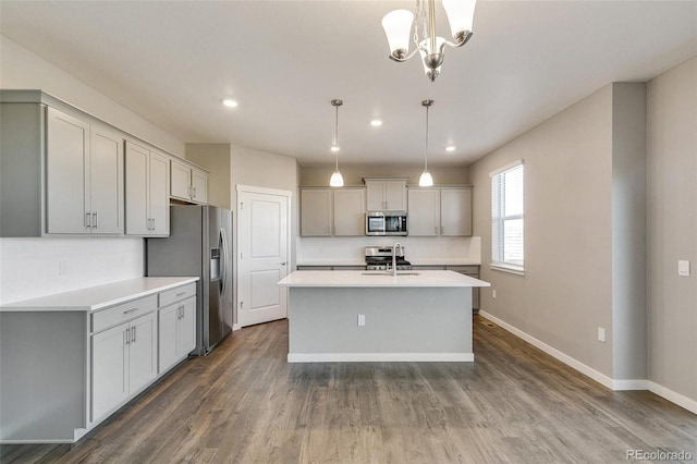 kitchen with sink, gray cabinets, an island with sink, decorative light fixtures, and stainless steel appliances