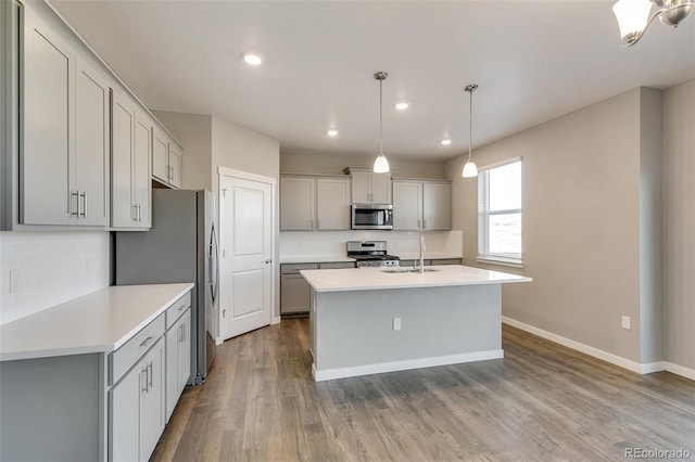 kitchen with gray cabinetry, stainless steel appliances, sink, decorative light fixtures, and hardwood / wood-style flooring