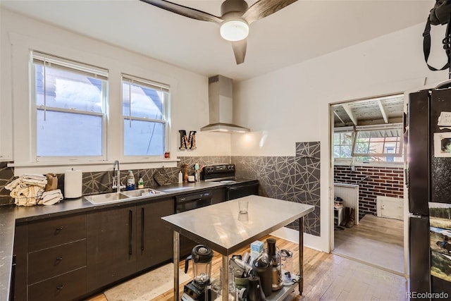 kitchen featuring sink, dark brown cabinetry, black appliances, a healthy amount of sunlight, and wall chimney exhaust hood