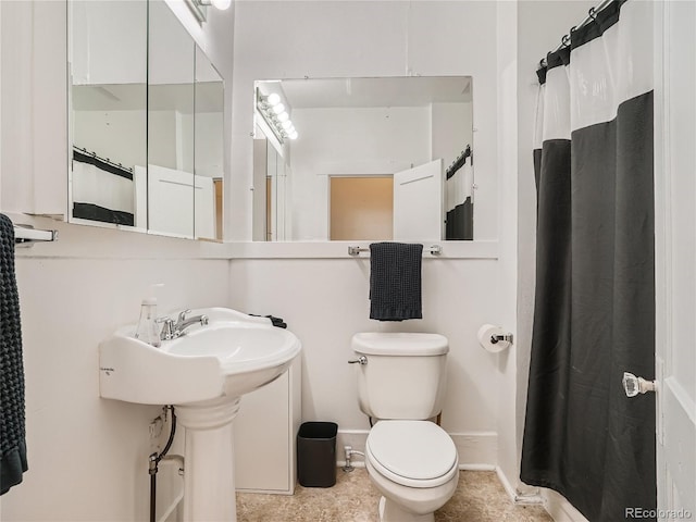 bathroom with toilet, curtained shower, and sink