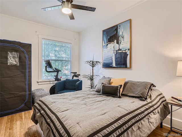 bedroom featuring hardwood / wood-style floors, ornamental molding, and ceiling fan