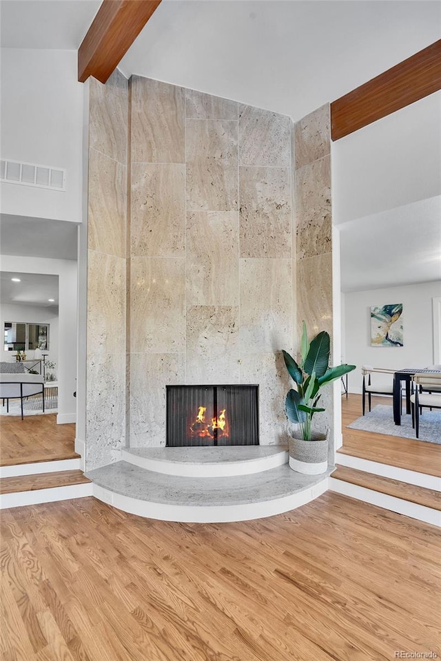 room details featuring wood-type flooring, a large fireplace, and beamed ceiling