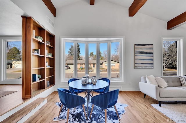 dining area featuring vaulted ceiling with beams, a baseboard radiator, and light hardwood / wood-style floors