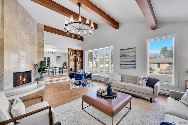 living room with wood-type flooring, a premium fireplace, vaulted ceiling with beams, a notable chandelier, and a baseboard radiator